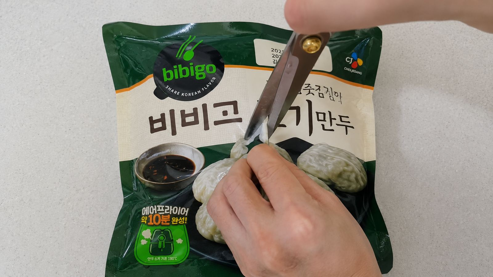 가위로 냉동만두 봉지 앞면에 칼집을 내는 모습